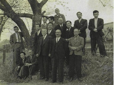 桜の下で教職員の記念写真